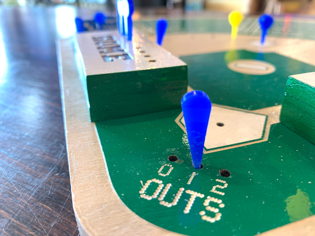 Baseball-themed game board with dice and markers on a wooden surface