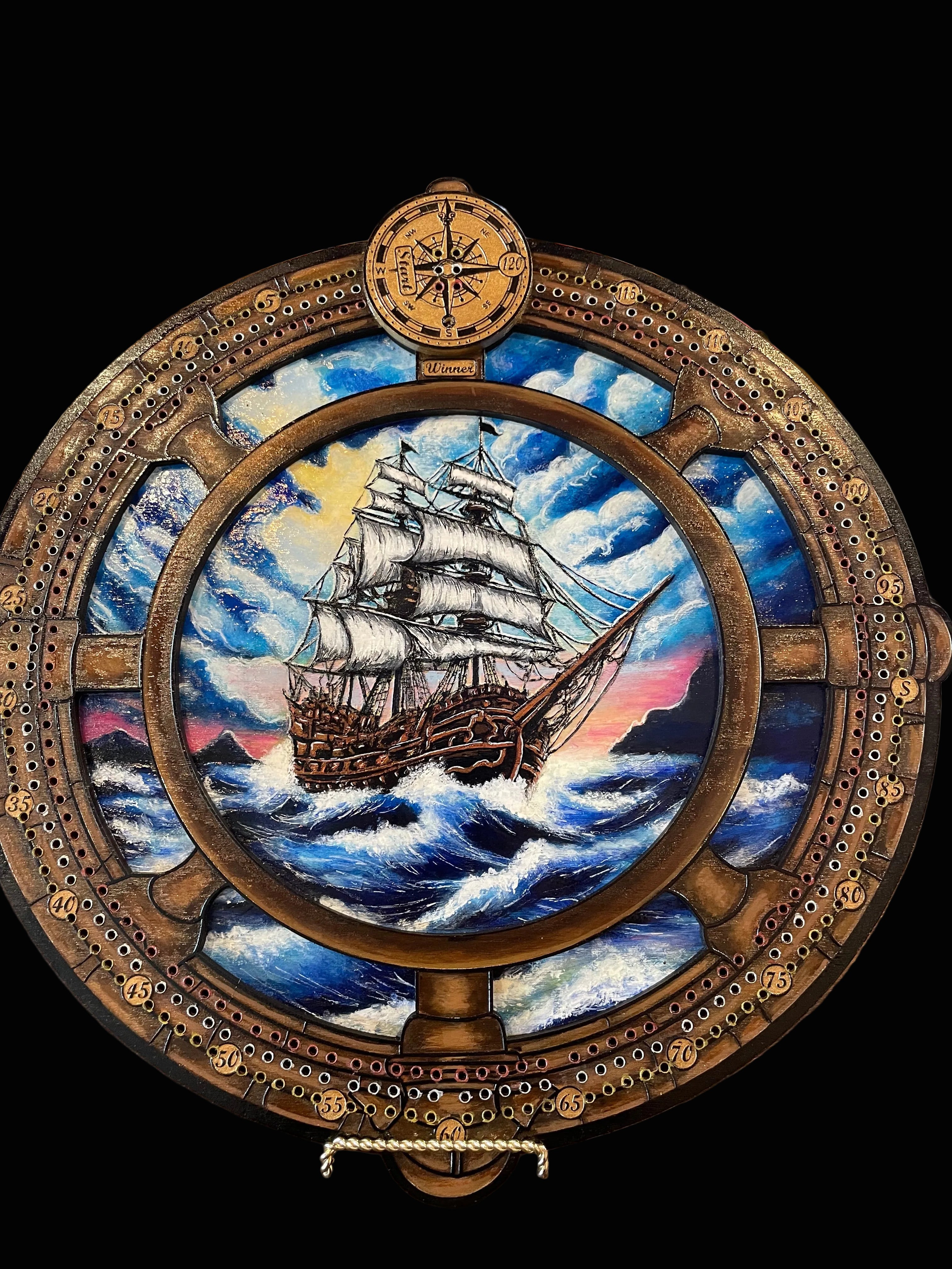 Decorative compass and ships wheel with ship illustration on a crib board