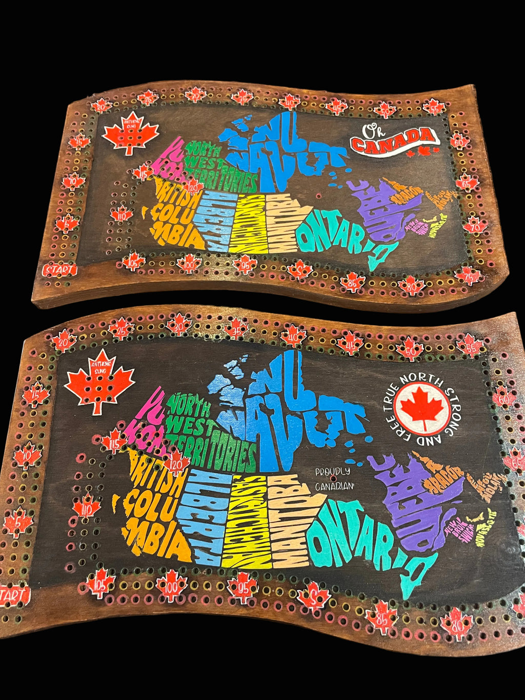 Two decorative wooden crib boards with colorful text and designs on a wooden surface.