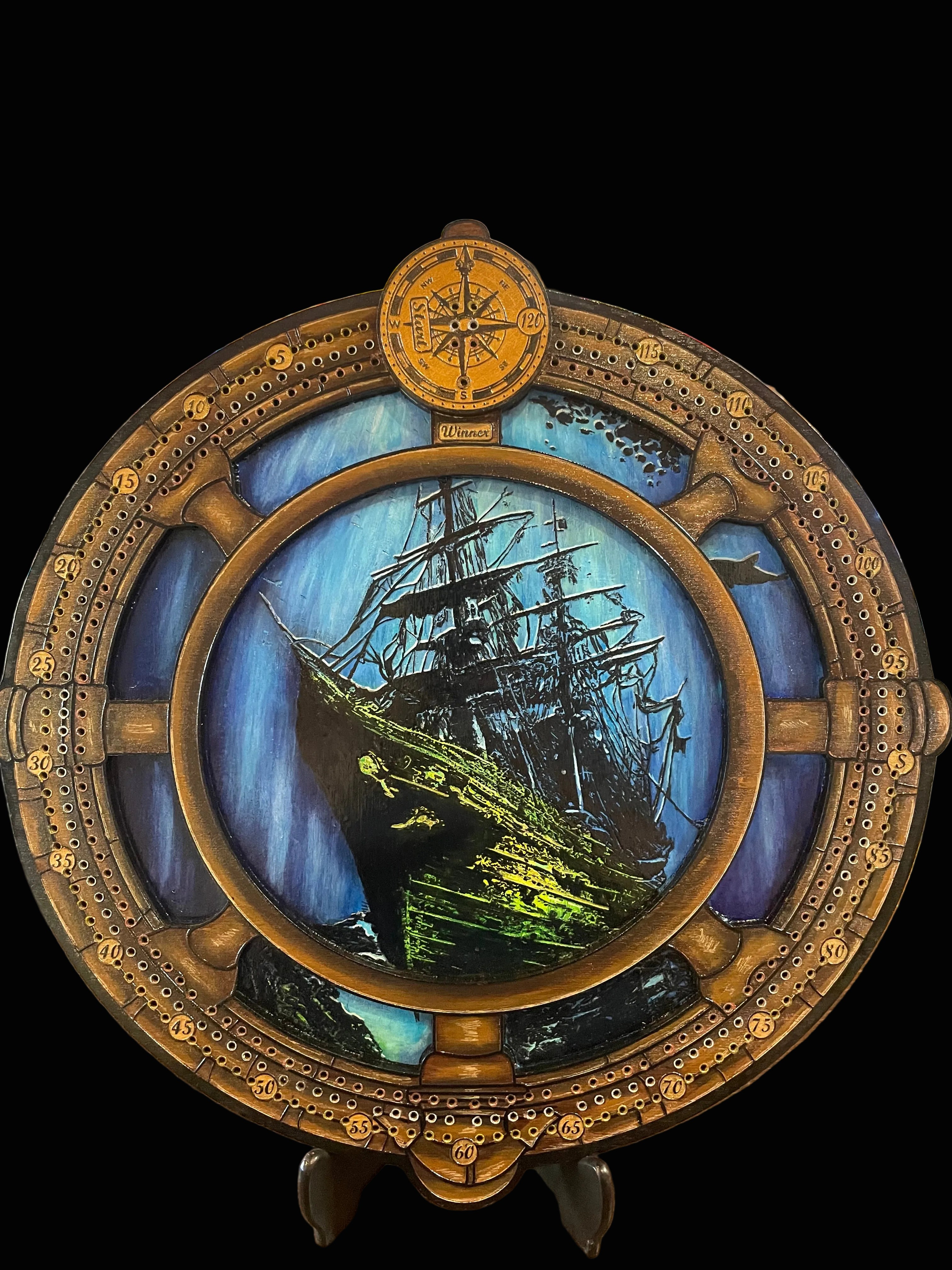 Decorative compass and ship wheel cribbage board with sunken ship.