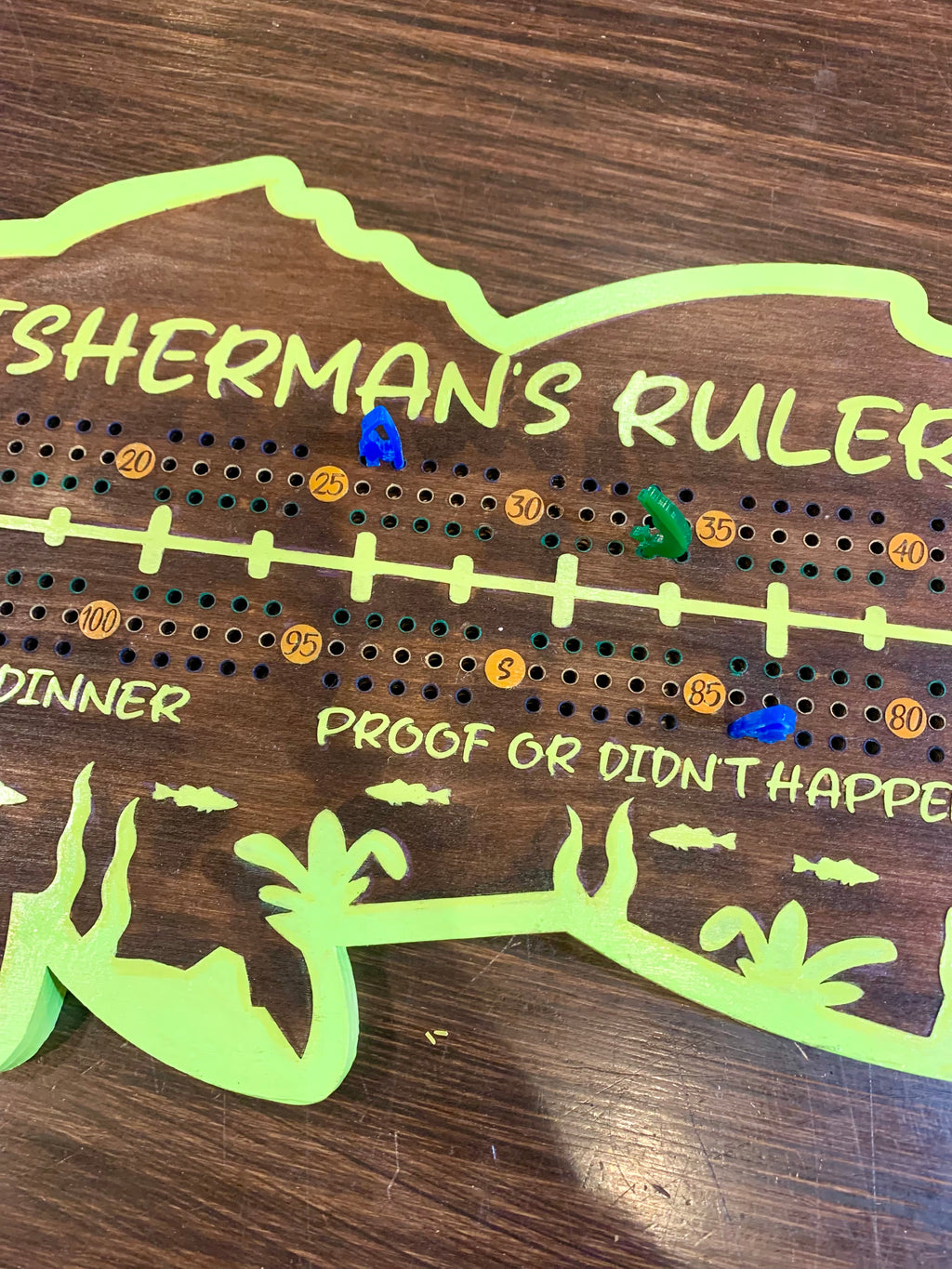 Wooden crib board with green text and acrylic pegs.