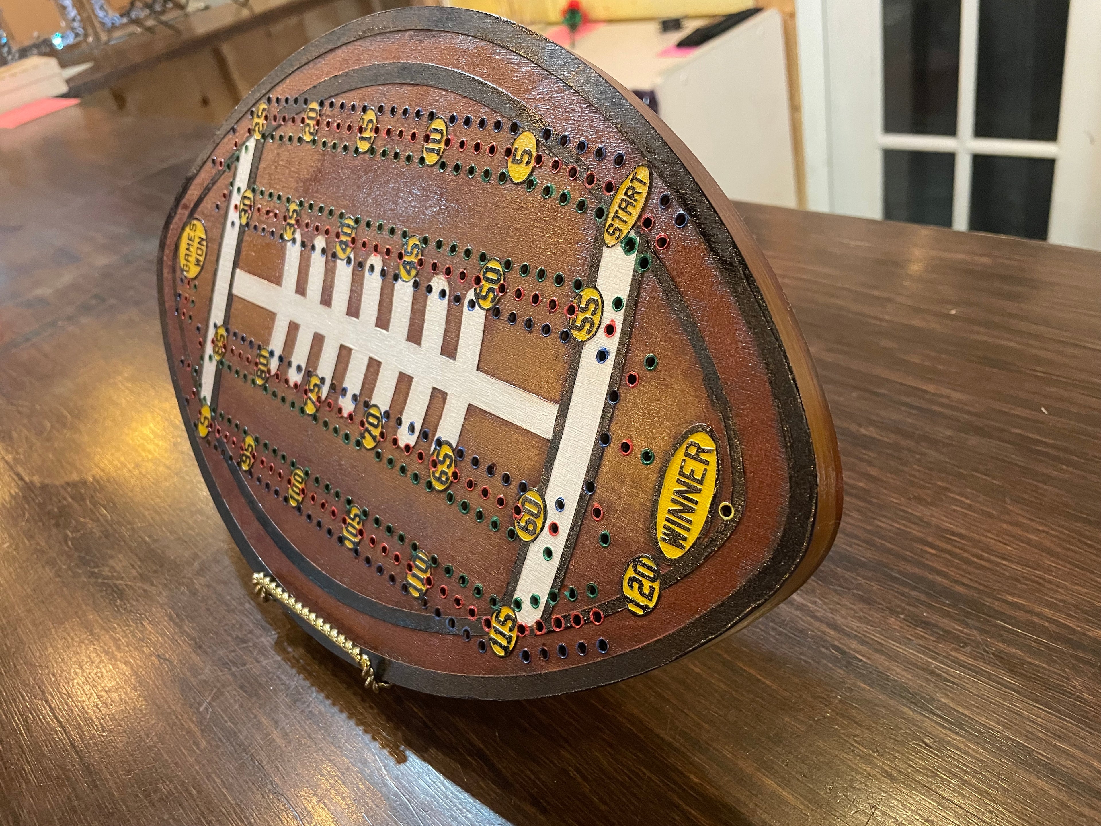 Wooden cribbage board shaped like a football.