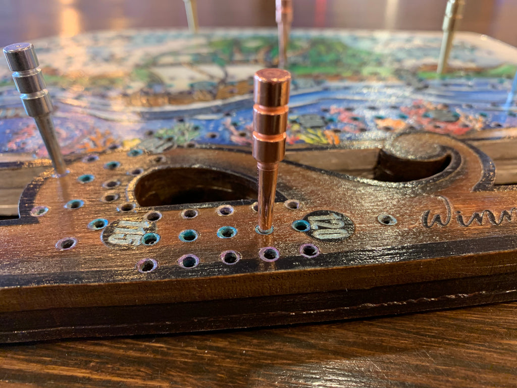 Close-up of a crib board with metal pegs.