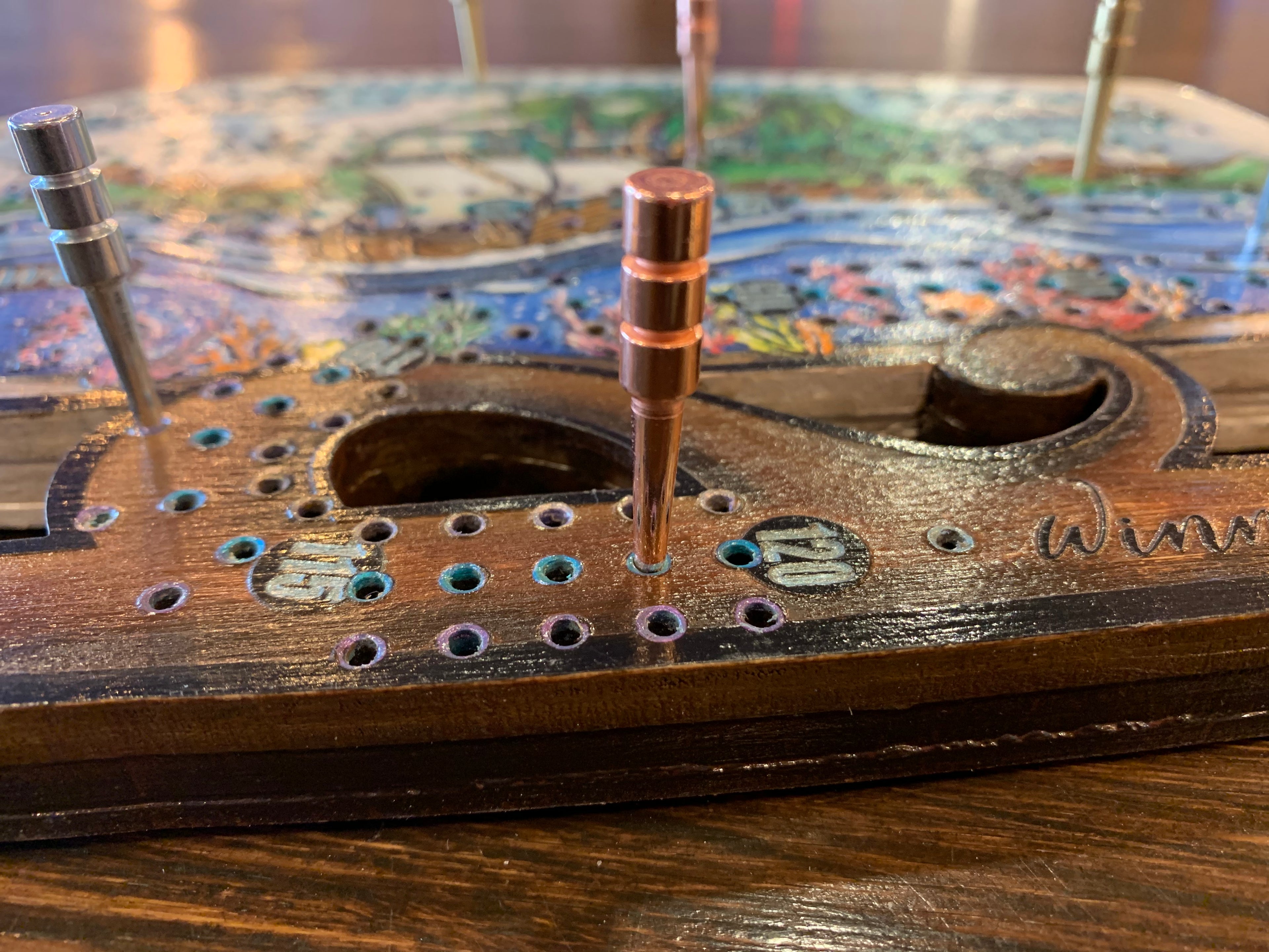 Close-up of a crib board with metal pegs.