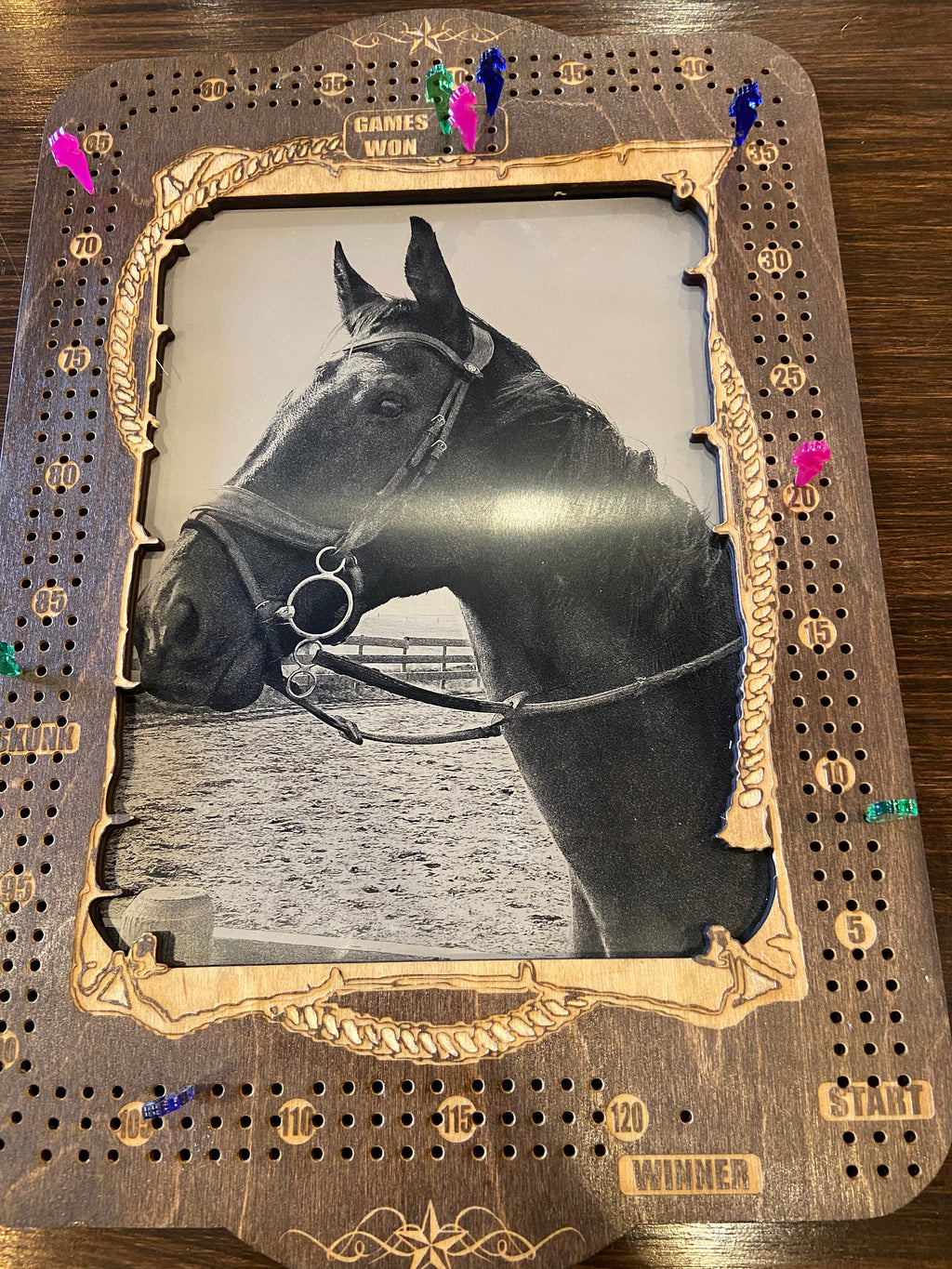 Horse headshot framed with decorative border on a wooden cribbage board.